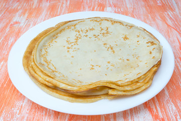 stack of fried thin pancakes on wooden background
