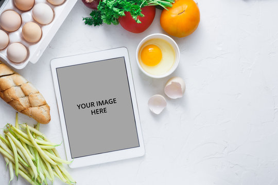 Tablet computer with fresh vegetables on white background, copy space