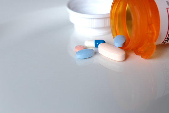 Pills Spilling Out Of Pill Bottle On White Background