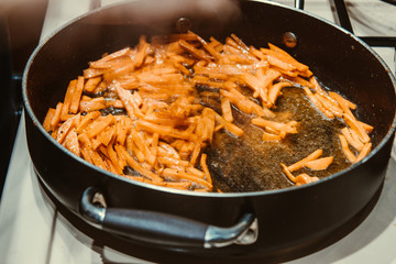 Carrots are fried in a pan