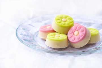 Chocolate candy with bright design on glass plate. Confectionery on a white background.