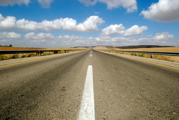 Endless road to nowhere running into the horizon blue sky with clouds