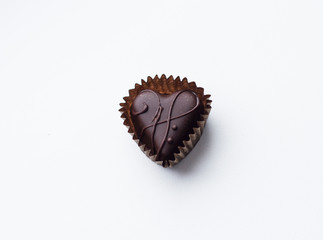 Chocolate candy in shape heart on white background, close up. Tasty candy, top view, flat lay. Dessert for gourmet. Sweet gift on Valentines or Mother Day. Love concept.