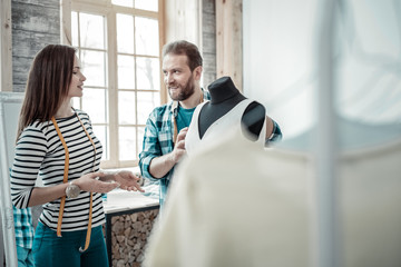 Dark-haired wife designing clothes with her husband