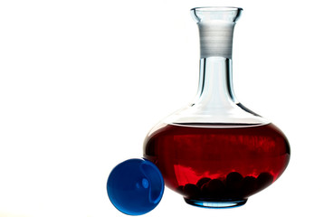 Blue glass decanter with spherical cap and red cherry drink isolated on white background.