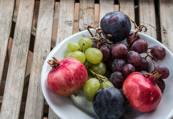 Fruit in Decorative bowl - overhead and depth of field. Pomegranates, grapes and plums - fresh and delicious