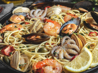 Cooked pasta with clams, shrimps, baby octopus, mussels tomato on a frying pan , spaghetti. Close up