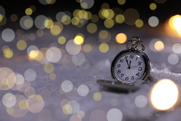 Fototapeta na wymiar Pocket watch on snow against blurred background, space for text. Winter night
