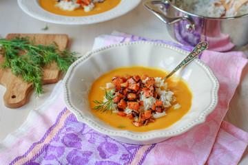 Healthy vegan pumpkin cream soup with rice, apples, roasted carrots and fresh herbs