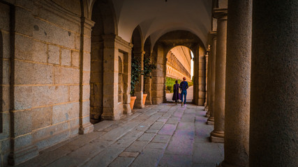People walk between columns at Frailes garden at the El Escorial monastery and royal site during fall time near Madrid, Spanish capital.