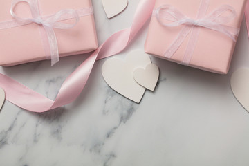 Pink valentine gift with white hearts on a marble background