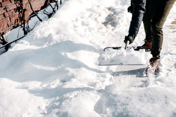 Man cleaning snow from car alley. Details of male using snow shovel
