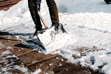 Close up details of working man cleaning out snow from house alley or path using snow shovel