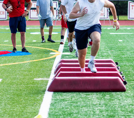 Footaball player running over barriers at preseason practice