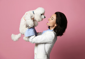 Beautiful woman hugging her lovely white poodle dog puppy on pink happy smiling