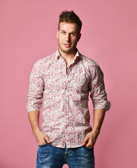 Young successful happy smiling business man in shirt and blue jeans standing posing on pink...