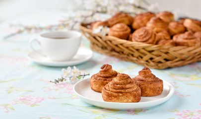 Cinnamon buns with tea and spring flowes on a table