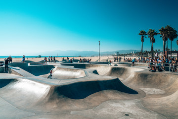 June 10, 2018. Los Angeles, USA. Venice beach skate park by the ocean. People skating at the skatepark showing different tricks.  - obrazy, fototapety, plakaty
