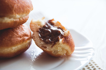 donuts with chocolate filling on white plate, white wooden background
