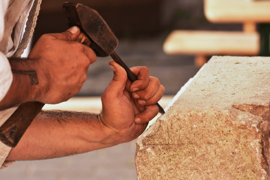 Closeup of a carpenter hands working with a chisel and carving tools on wooden 
