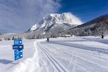 Schilderijen op glas Winter mountain landscape with groomed ski trails and blue sky in sunny day. Ehrwald valley, Tirol, Alps, Austria, Zugspitze Massif  in background. © msnobody