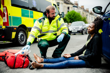 Male paramedic checking on an injured woman on a road © Rawpixel.com