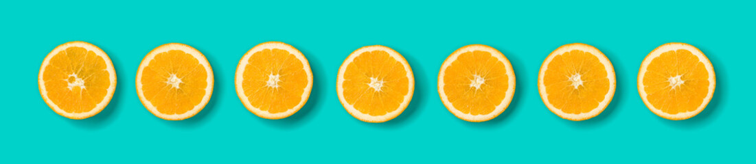 Fruit pattern of orange slices on blue background. Flat lay, top view. Banner, seamless pattern, creative summer food concept.