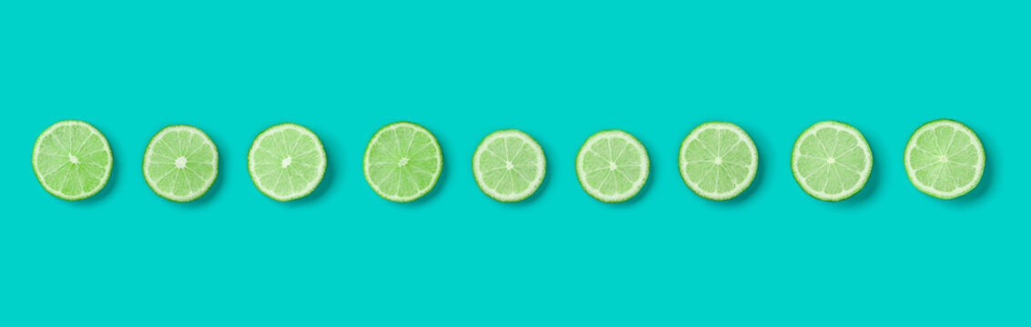 Fruit pattern of lime slices on blue background. Flat lay, top view. Banner, seamless pattern, creative summer food concept.