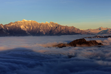 Mountains floating above the sea of clouds, appearing like islands an ocean - Niubeishan Landscape, Cattle Back Mountain, Sichuan Province China. Snow mountains, fluffy clouds, majestic china scenery
