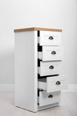 Stylish chest of drawers near white wall. Furniture for wardrobe room