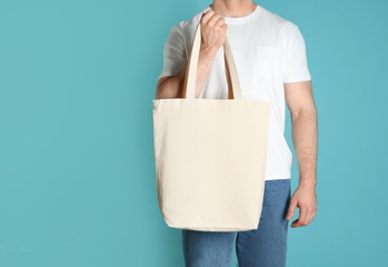 Fototapeta na wymiar Man with cotton shopping eco bag on color background. Mockup for design