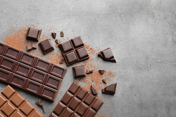 Different kinds of chocolate on grey background, flat lay. Space for text