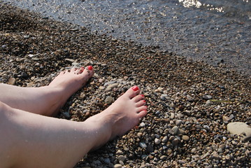 Female  legs at the waterline on a beach 