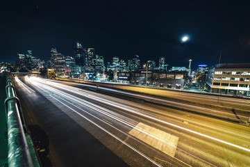 Fototapeta na wymiar Freeway Cityscape of Car Streaks and Seattle Skyline Building Lights Under Moon