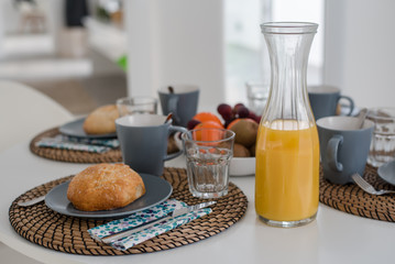 Plate with fresh crusty bread and glass of juice on grey plate