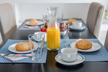 Plate with fresh crusty bread and glass of juice on white plate