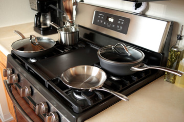 Modern stainless steel gas stove oven in a home with various cookware.