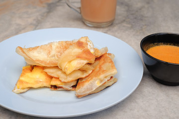 Tea with milk, Roti canai or Roti Parata and curry sauce on the plate over wooden  table