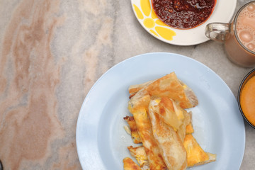 Tea with milk, Roti canai or Roti Parata and curry sauce on the plate over wooden  table