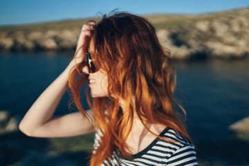 red-haired woman in glasses against the background of the sea
