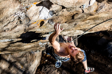 rock-climber man screaming for tension holding on to a rock with one hand, close-up