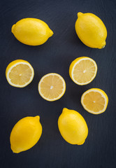 Whole and cut lemons on dark background