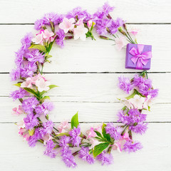 Floral frame of pink flowers and ring box on white rustic background. Flat lay, top view