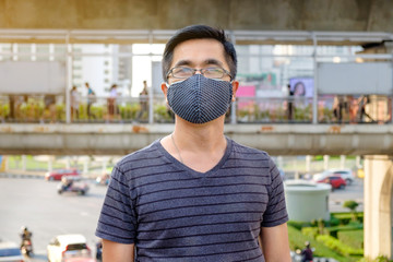 A man wearing eyeglass and black mouth mask against air pollution with PM 2.5 in Bangkok Thailand