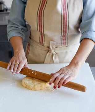 Woman Rolling out pie dough wearing striped apron