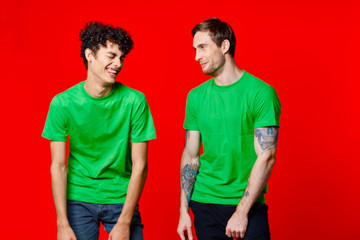 friends in green t-shirts laughing on a red background