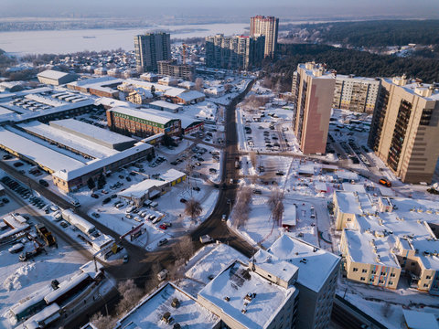 Aerial city view with crossroads, roads, houses, buildings, parks, parking lots, bridges in winter day,  there is a lot of snow around
