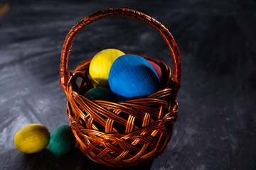 Easter multicolored eggs in a basket on a dark blurred background