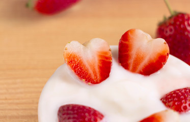 Bowl of yogurt and red fruit strawberry on the wood table. Yogurt made from milk fermented by added bacteria, often sweetened and flavored.