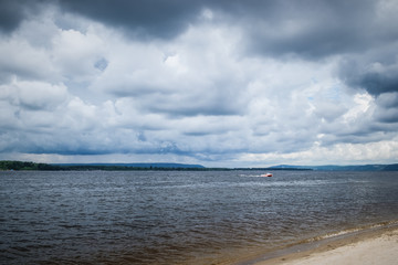 Big white clouds on the blue sky above the river.